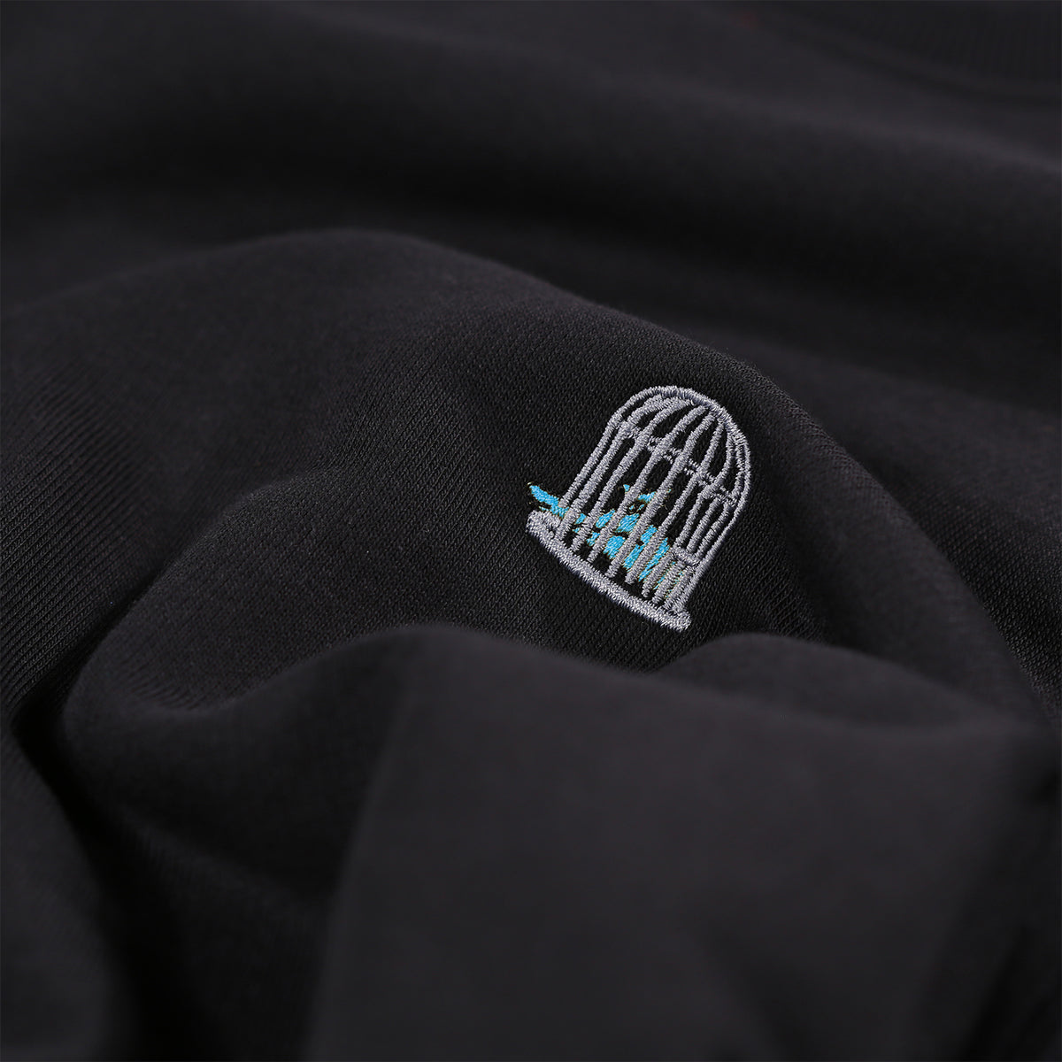 Detailed close-up of tonal embroidery on black men’s organic cotton sweatshirt