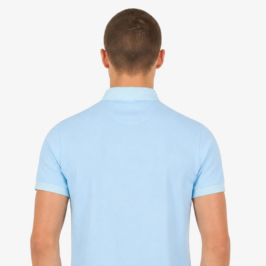 Rear studio shot of a white male model wearing the Sauce & Brown Calma light blue polo shirt against a clean white background.