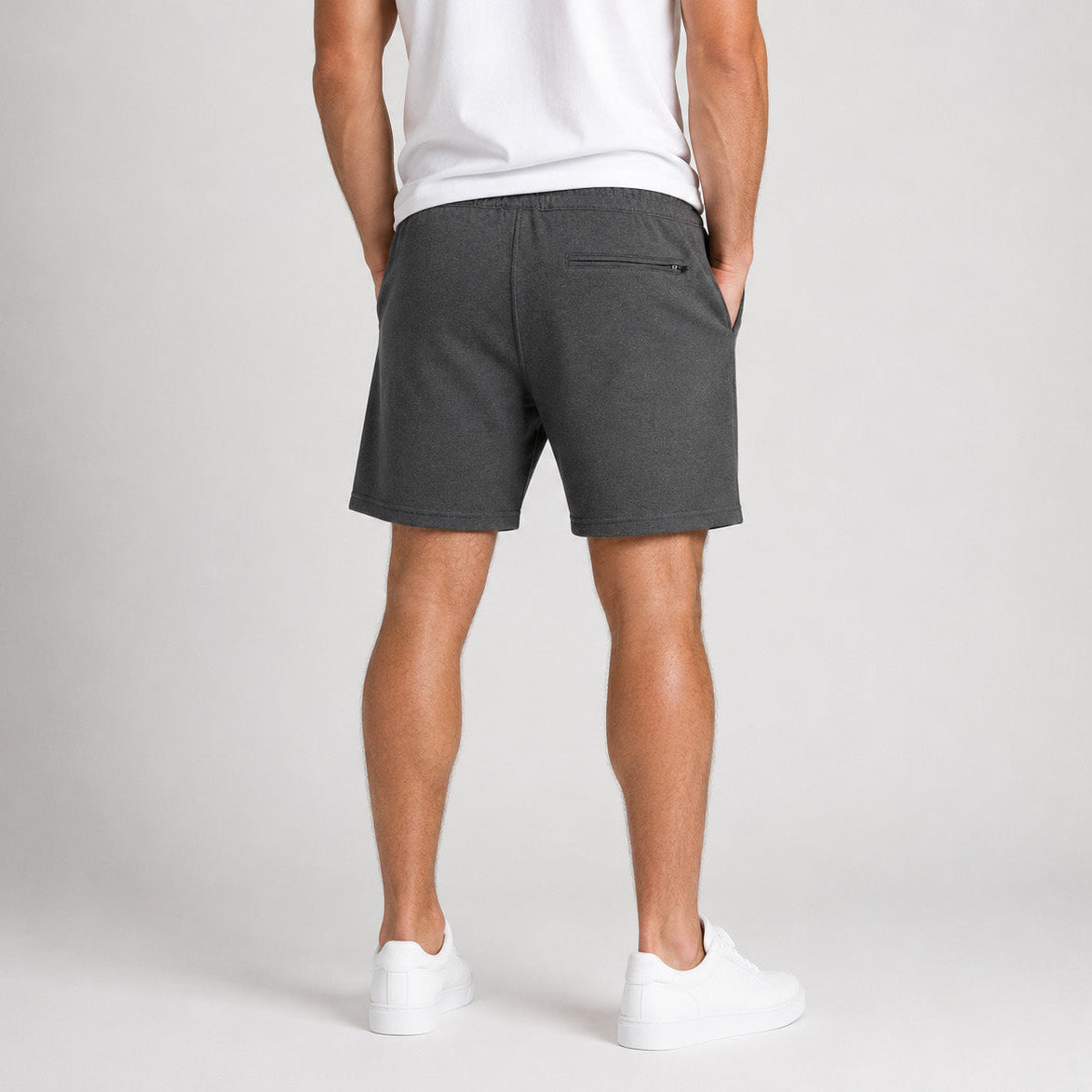 Rear studio photograph of a male model wearing the Sauce & Brown Quarry dark grey marl jogger shorts with YKK zipped rear pocket.