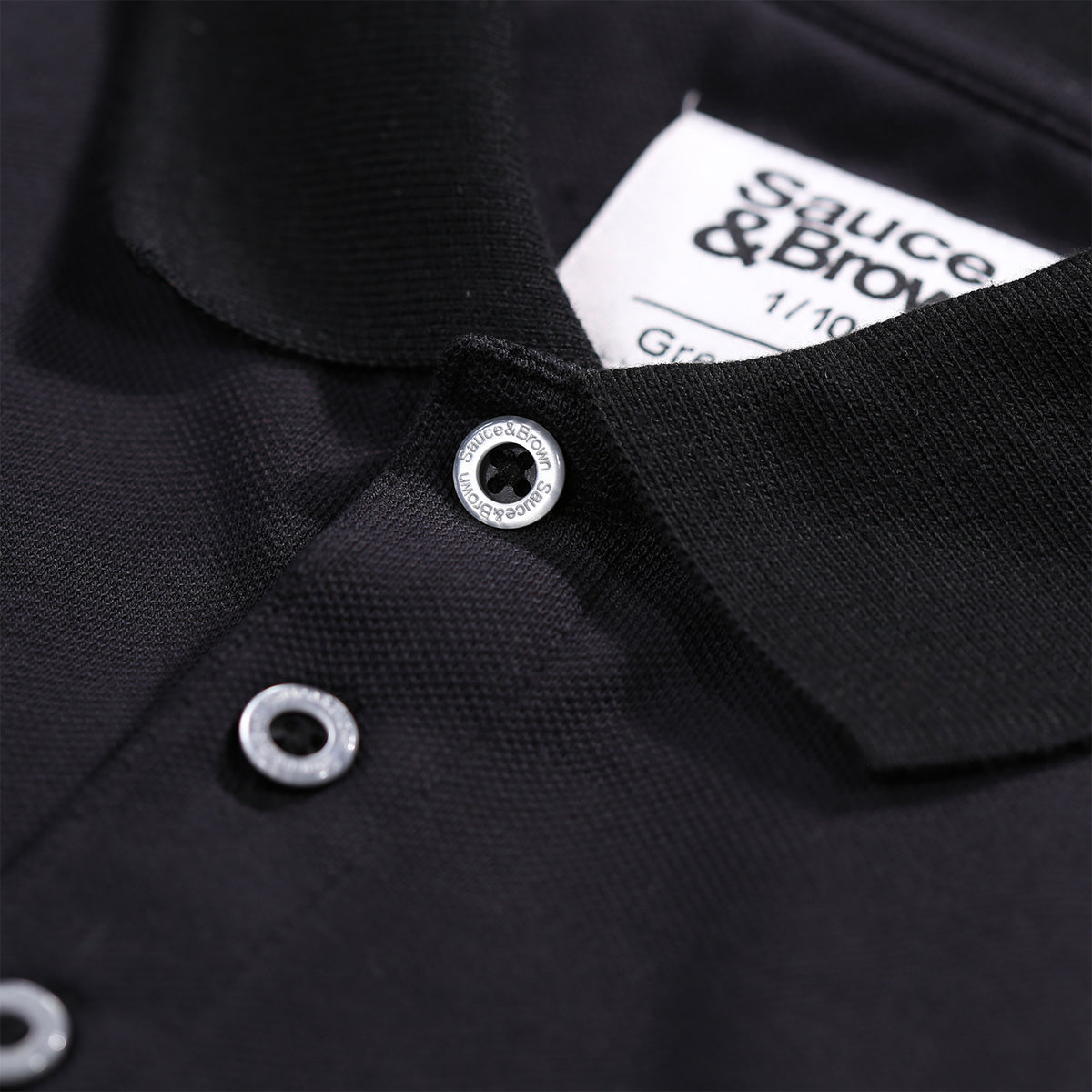 Close-up collar detail of Coaled Polo in black by Sauce & Brown