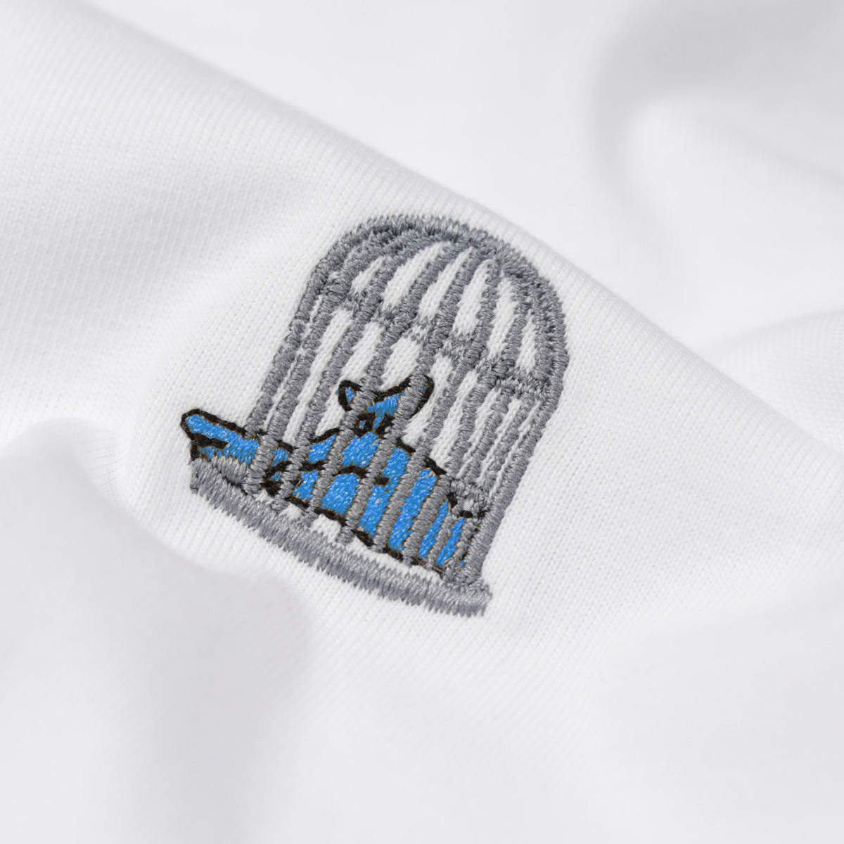 Detail of birdcage embroidery on men’s white t-shirt by Sauce & Brown